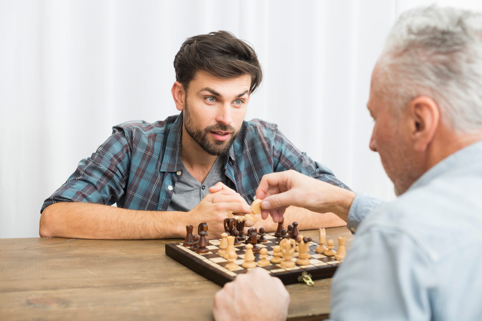 Jogador experiente e jovem disputando uma partida à mesa